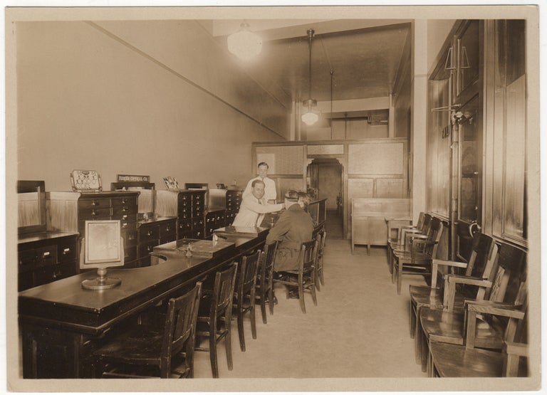 Item #008844 A photograph of the interior of the Optical Service Company as well as the proof copy of an advertisement for the business that was published in the St Louis Post-Dispatch. Unknown photographer.